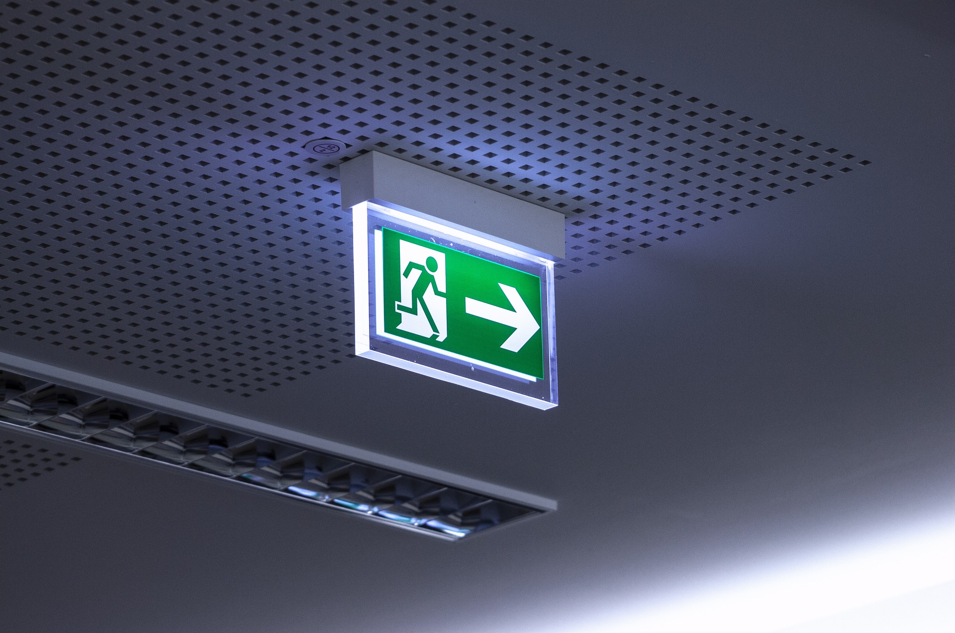 Panneau lumineux suspendu à un plafond, indiquant une issue de secours