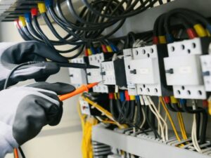 Électricien réalisant un contrôle sur un tableau électrique dans le cadre de la surveillance médicale des salariés habilités électriques.